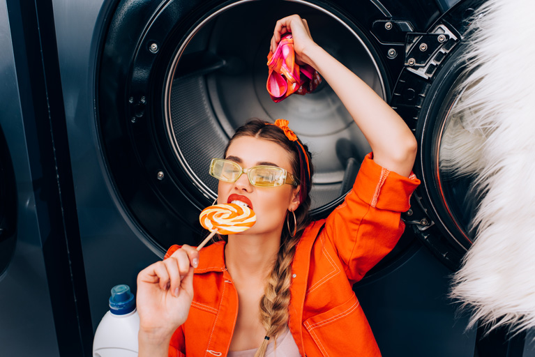 Woman biting a lollipop while doing laundry
