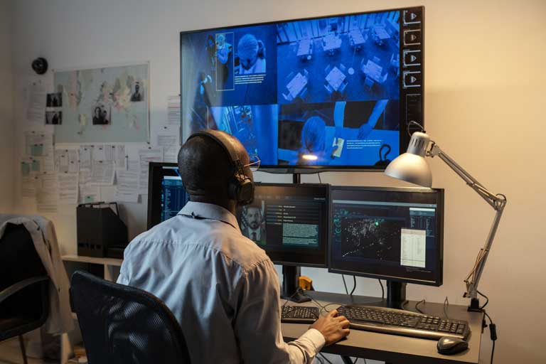 An African American man watching security footage at his desk