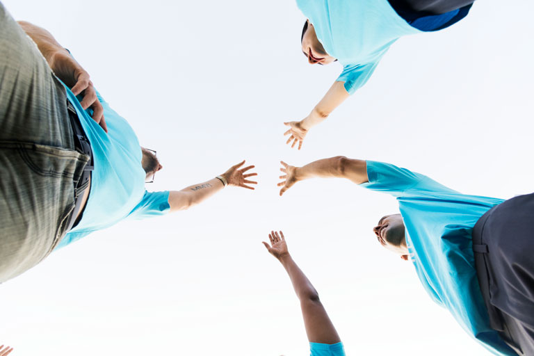 4 people holding up their hands to the sky