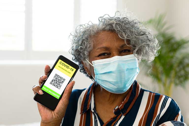 An older African American woman holding up her COVID-19 vaccination certification on her phone.