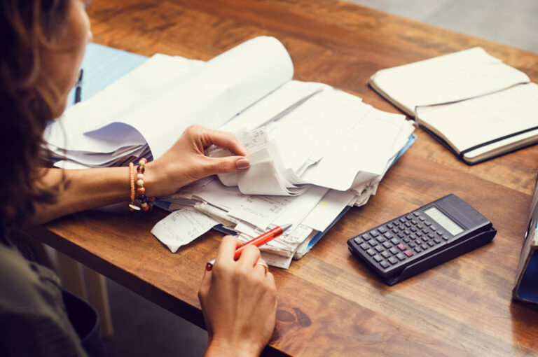 Woman checking stacks of receipts with a calculator next to her