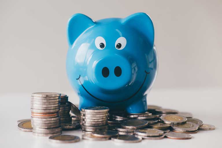 Blue Piggy bank standing on top of coins on a flat surface
