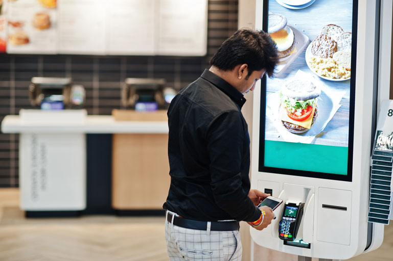 Man paying for fast food on a touchscreen kiosk inside the restaurant