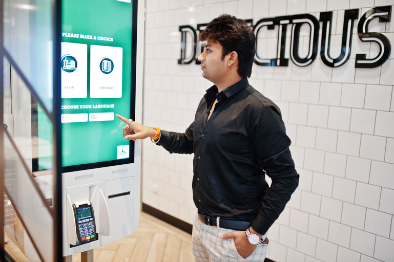 Man paying for a meal on a big touch screen inside a restaurant