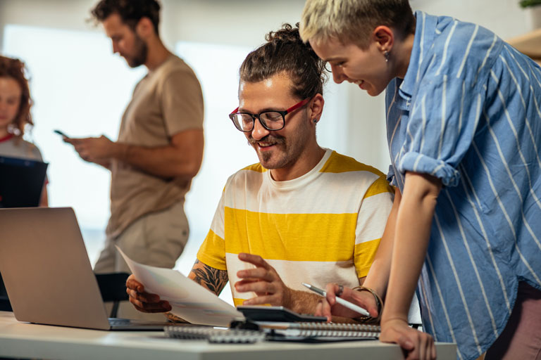 2 coworkers laughing while looking at a document