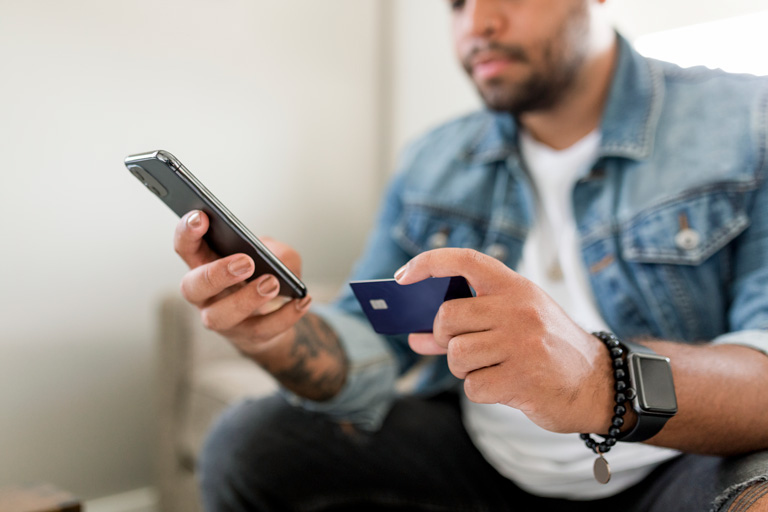 Man typing the numbers of his credit card on his phone to make an online purchase