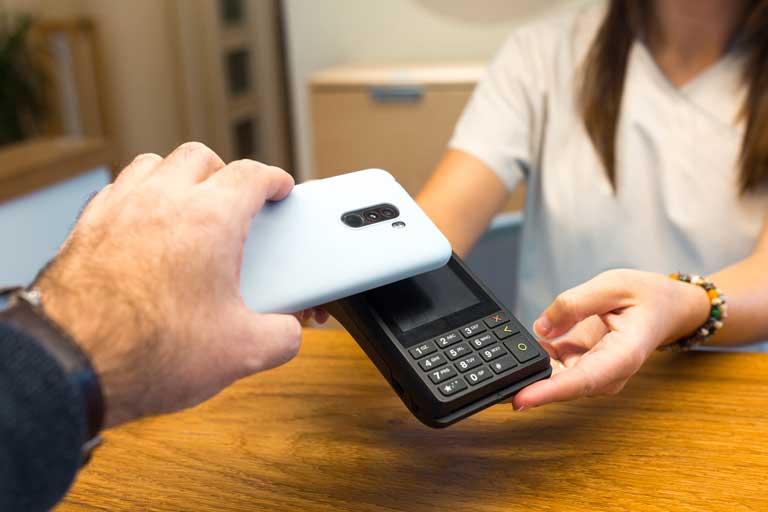 Man making a payment by holding his smartphone over a contactless payment terminal