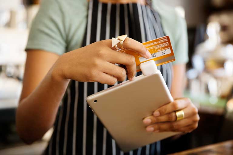 Barista swiping a credit card on a mobile pos attached to an smart tablet