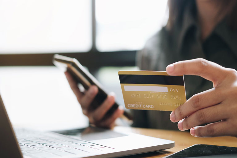 Woman making an online purchase on her phone while holding a credit card