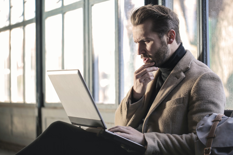 A man looking confused at his laptop