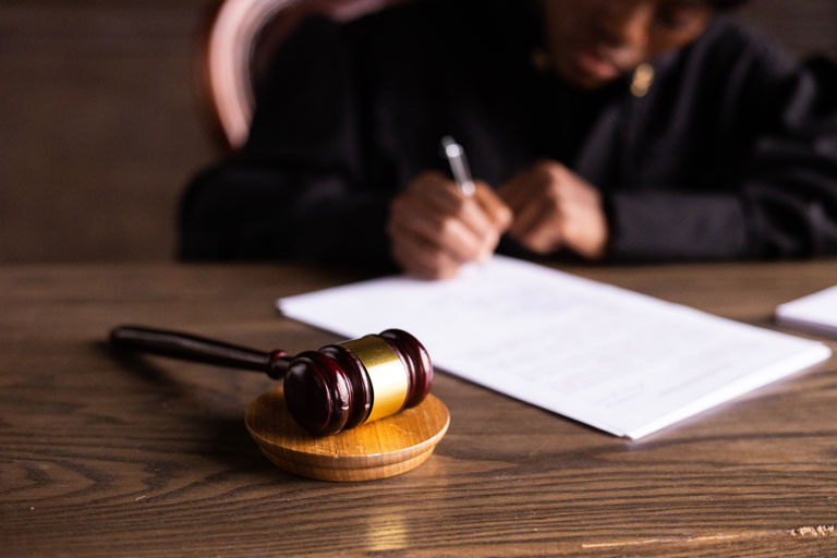 Judge with a gavel in front signing a sentence plea