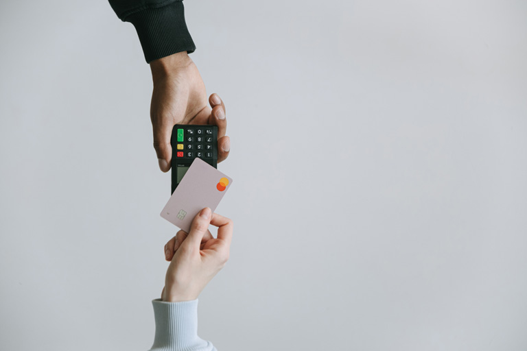 Woman holding a credit card to a wireless payment terminal