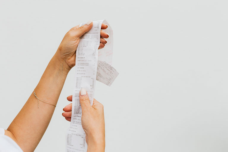 Woman holding a very long purchase receipt