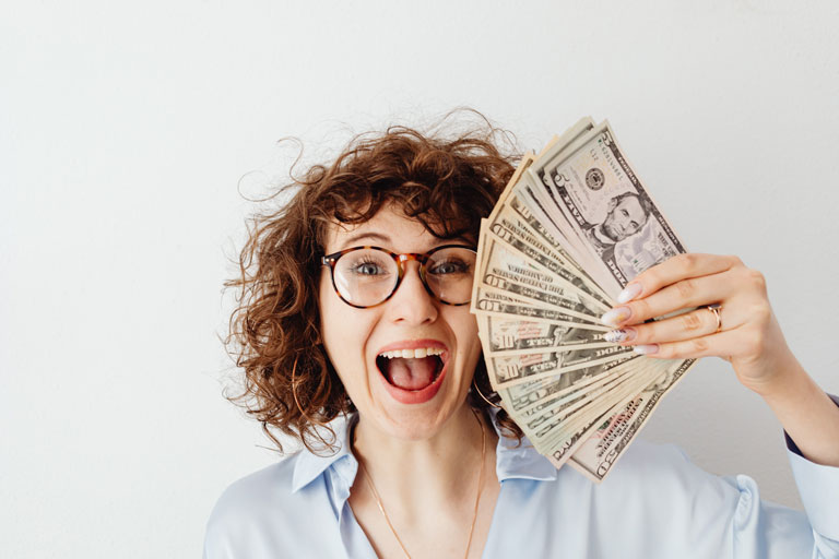 Happy woman with glasses holding up cash