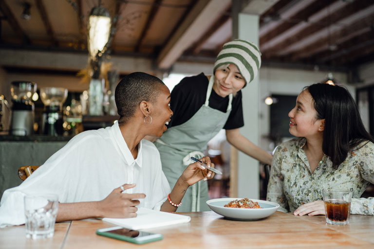 3 woman talking laughing and taking in a restaurant