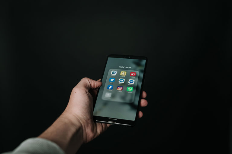 Person holding a smartphone showing social media apps on the screen