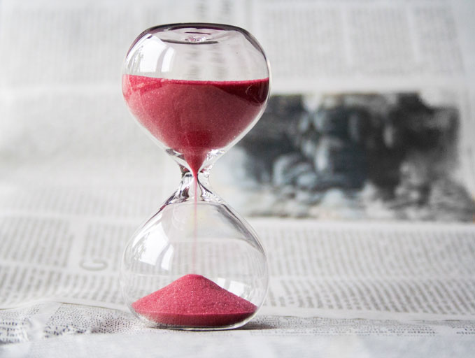 hourglass full of red sand on top of newspaper