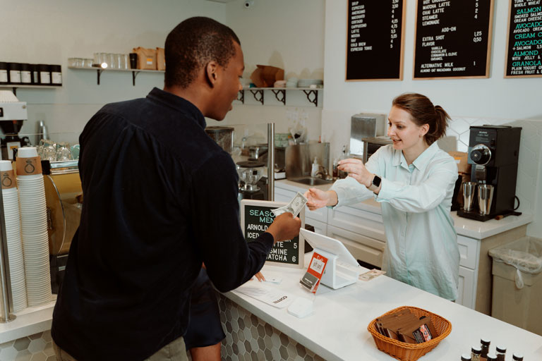 African american male customer paying for a coffee with cash