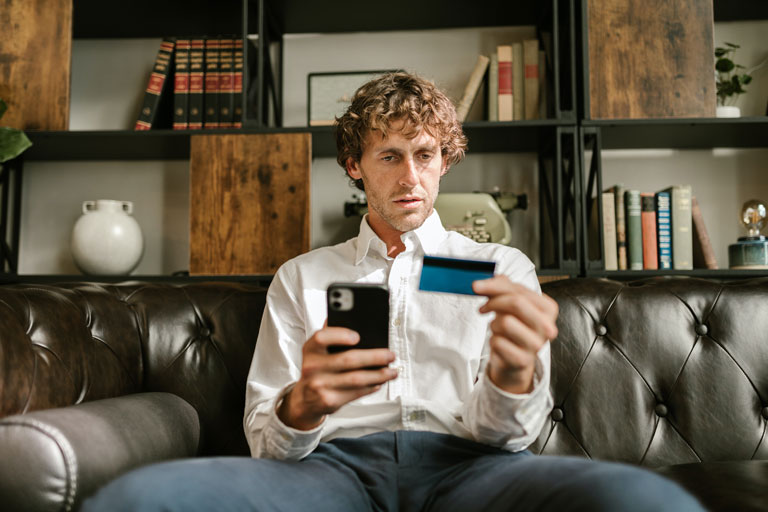 Men sitting down looking at the numbers on the back of a credit card