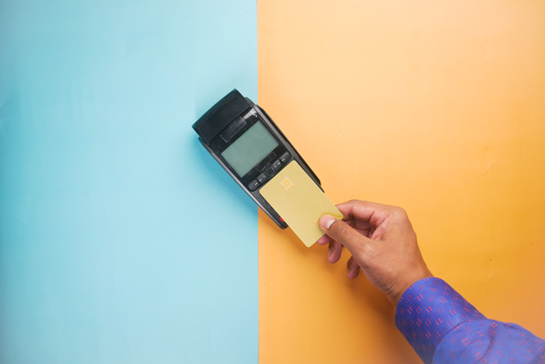 Man holding a credit card over a credit card payment terminal