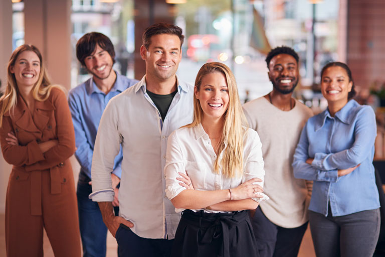 Multicultural professionals inside of an office smiling at the camera