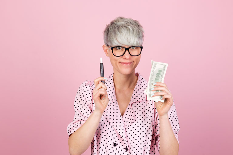 Woman holding an electronic cigarette in one hand and cash on the other