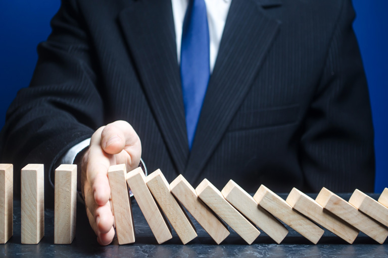 Businessman stopping wooden blocks from creating a domino effect