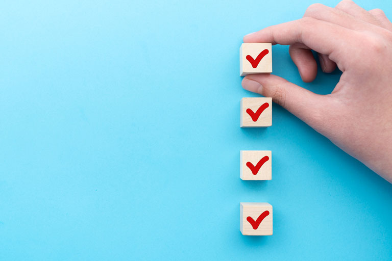 Woman's hand holding a wooden block with a red check mark, putting it on top of 3 more