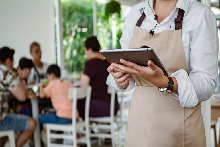 Hostess holding an ipad inside a restaurant