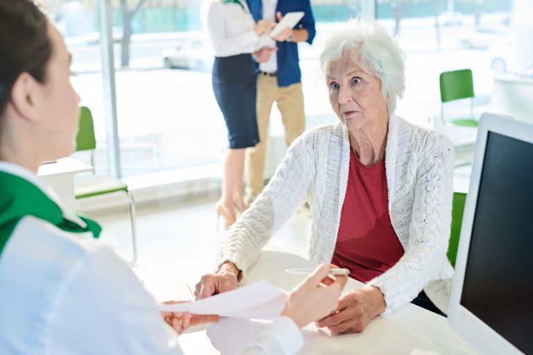 Elderly woman signing paperwork inside an office