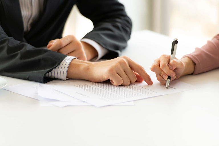 Business professional showing a woman where to sign a contract