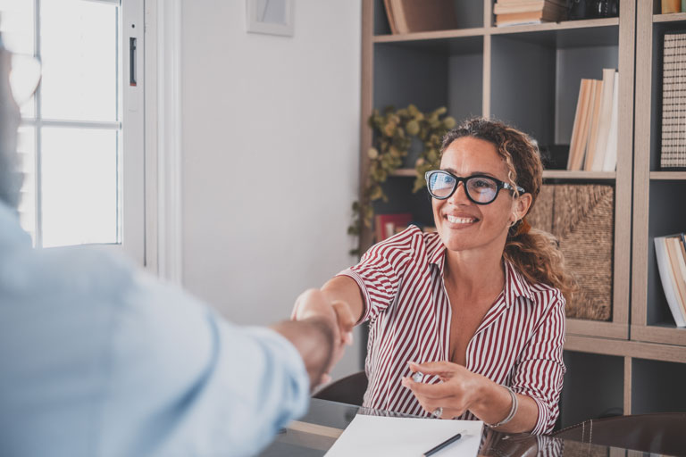 Smiling woman shaking man's hand inside an office