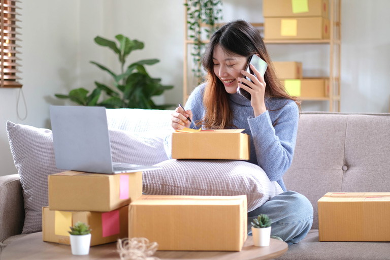 Small business owner taking orders over the phone from her living room using boxes to place her laptop