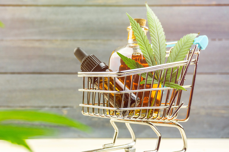 Shopping cart filled with cbd oil jars and a cannabis plant