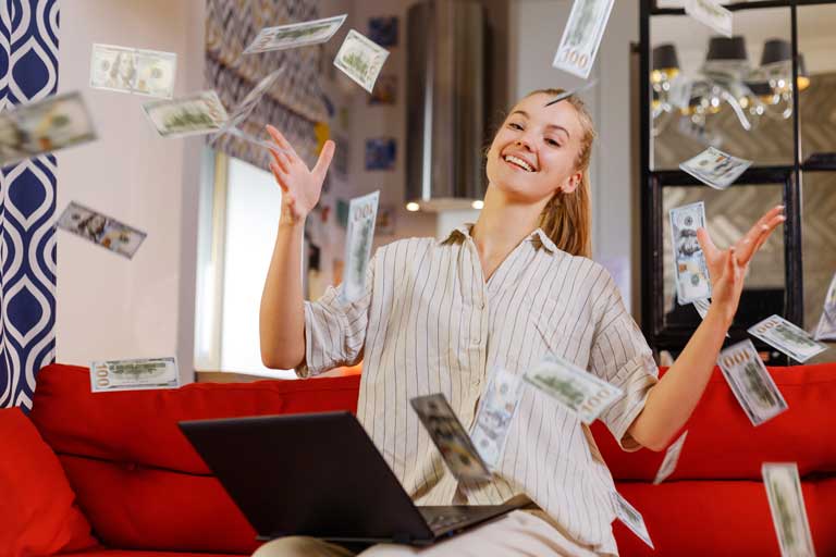 Happy young woman sitting down in a living room throwing cash