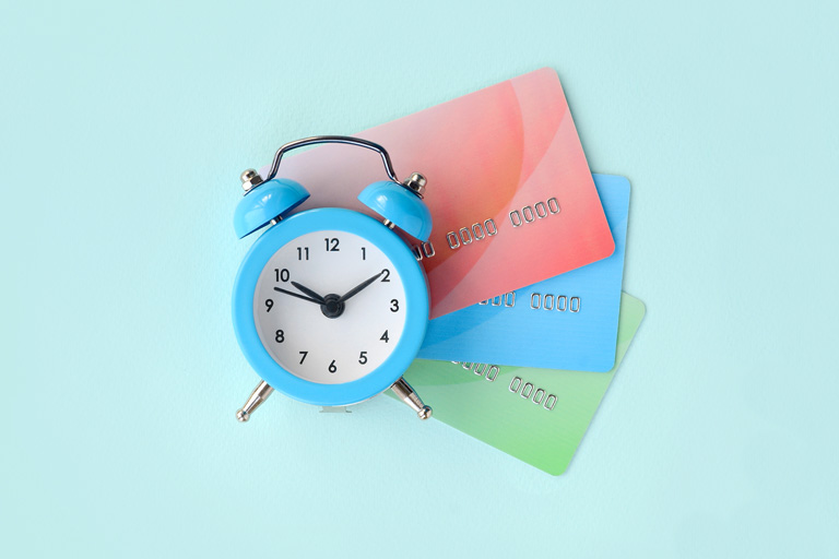 Blue clock laying on top of 3 credit cards