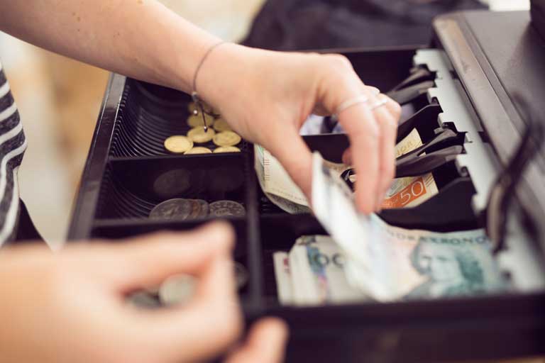 Woman taking bills out of a restaurants cash register