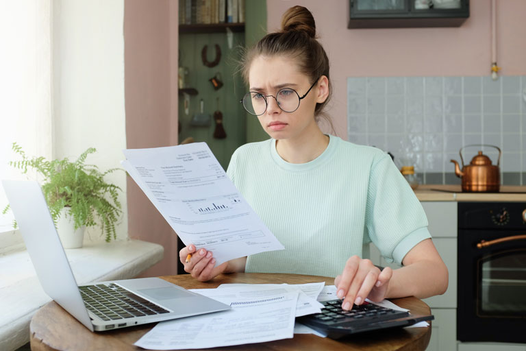 Frustrated young woman checking bank statements in her kitchen