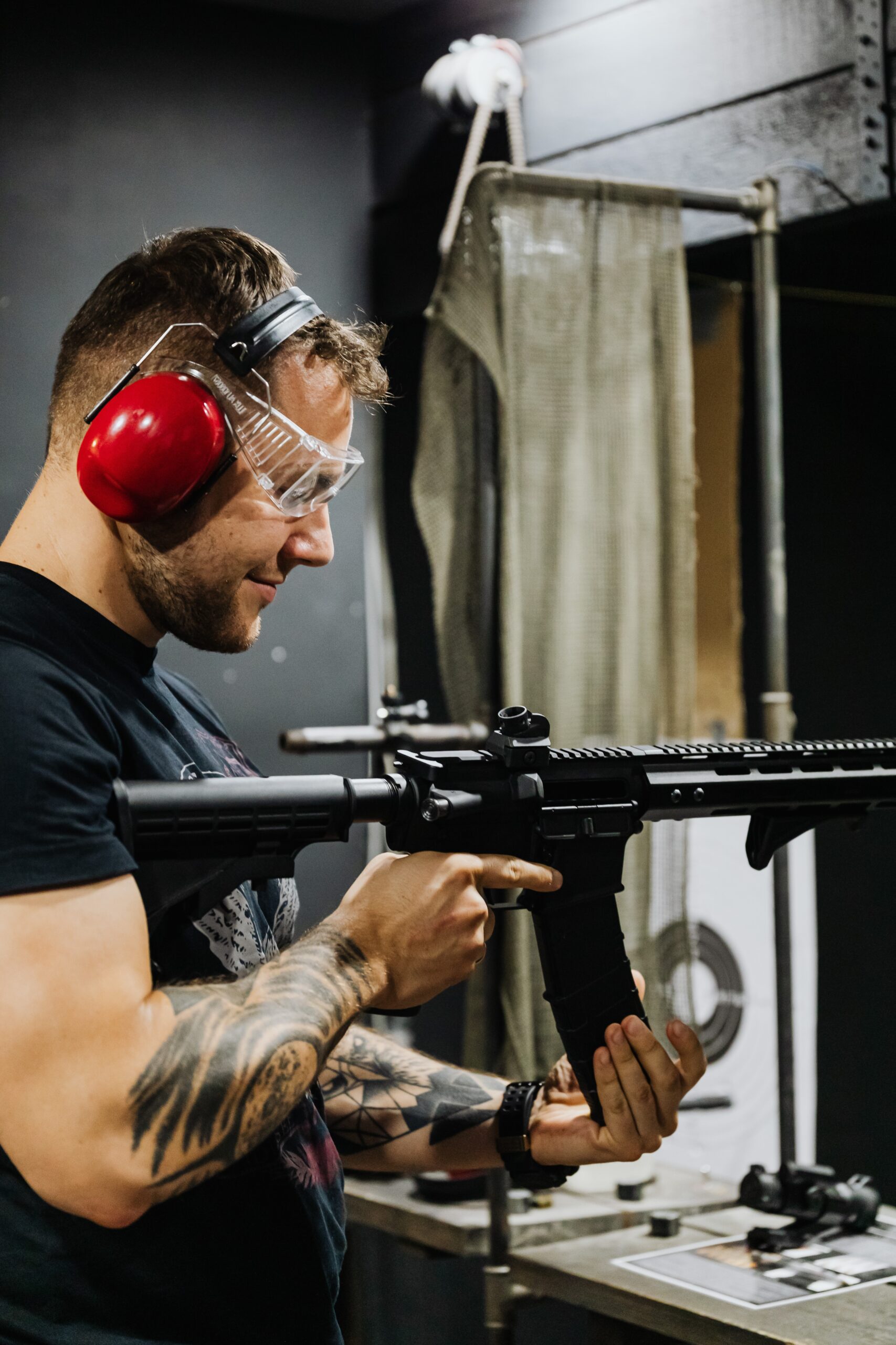 man holding a rifle, wearing headphones, and safety glasses