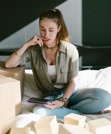 Small business owner holding a tablet and surrounded by boxes